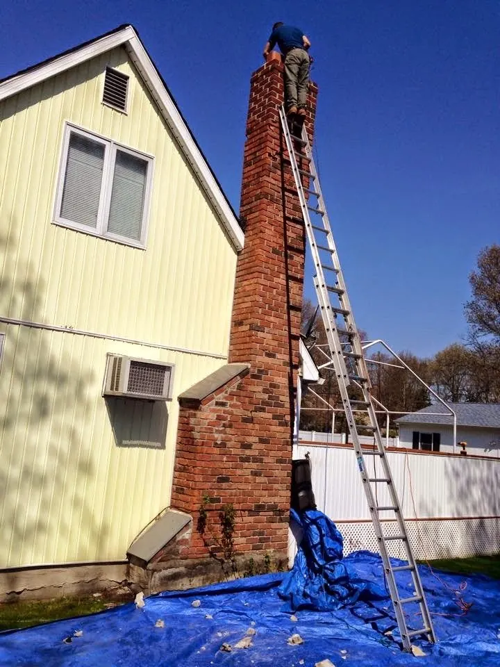 Masonry repair underway on a tall brick chimney stack