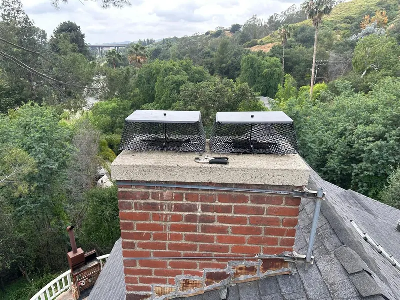 Twin stainless flue caps fitted on a brick chimney